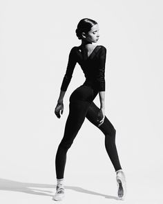 a black and white photo of a woman in tights with one leg bent forward