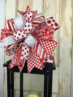 a large red and white bow on top of a table next to a candle holder