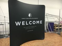 a black welcome sign with white lettering on it in a room filled with other furniture