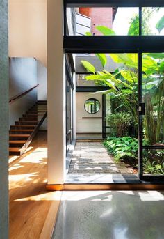 the inside of a house with lots of windows and plants on the outside side of the house