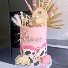 a pink and white cake with animals, farm animals, and letters on the top