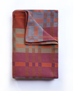 an orange and blue plaid blanket folded on top of a white surface