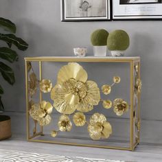 a glass table with gold flowers on it and two pictures above the table behind it