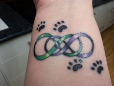 a person with a tattoo on their arm that has two intertwined rings and paw prints