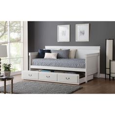 a white daybed with drawers underneath it in a living room next to a window