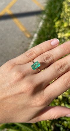 a woman's hand with a ring on it and a green stone in the middle