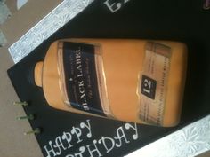 a birthday cake made to look like a bottle of black label liquor on top of a notebook