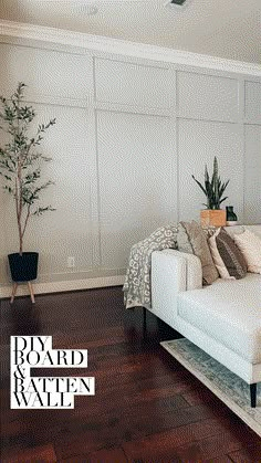 a white couch sitting on top of a wooden floor next to a potted plant