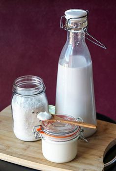 there are two jars and one is filled with white stuff on a wooden tray next to another jar