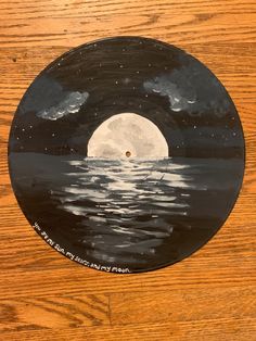 a wooden table topped with a painting of the moon and water on top of it