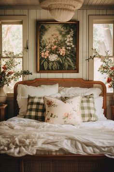 a bed with white sheets and pillows in front of two large paintings on the wall