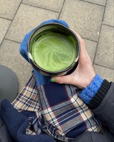 a person holding a cup with green liquid in it