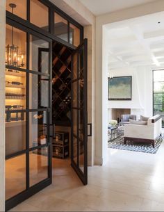 an open glass door leading to a wine cellar in the middle of a living room