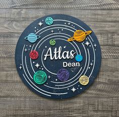 a sign that says atlas dean on the side of a wooden wall with space and planets around it