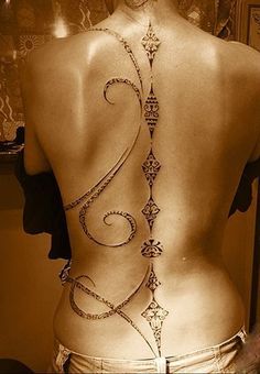 the back of a woman's body with an intricate tattoo on her lower back