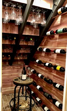 a wine cellar with many bottles and glasses on the wall next to a small table