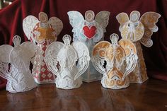 several paper angel figurines sitting on top of a wooden table