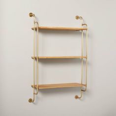 a shelf with three shelves and two hooks on the wall, against a white background