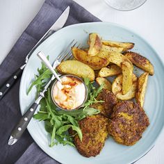 a white plate topped with food next to a fork and knife on top of a table