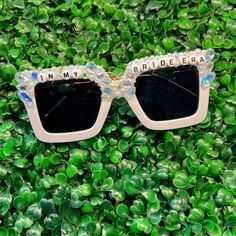 a pair of sunglasses with the words in my bridesma written on them sitting on some green plants