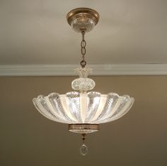 a chandelier hanging from the ceiling in a room with beige walls and white trim