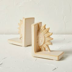 two wooden bookends with an ornate sun design on the front and back sides