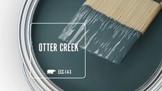 a paint can with the words otter creek painted on it and a brush in front of it