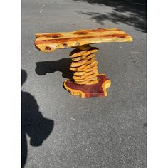 a wooden bench sitting on top of a parking lot next to a tree branch structure