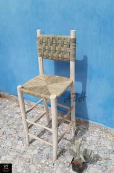 a wooden chair sitting in front of a blue wall next to a potted plant