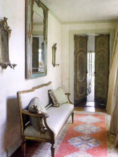 a living room with a couch and mirror on the wall next to an ornate doorway