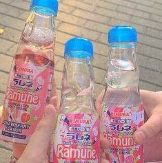 two bottles of ramune are being held by someone