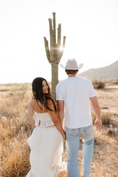 a man and woman walking in front of a cactus