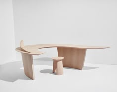 a curved wooden table and stools in an empty room