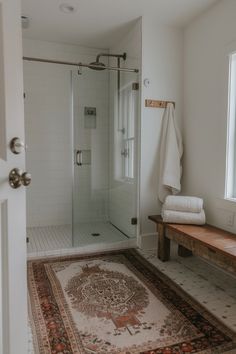 a bathroom with a rug on the floor next to a shower stall and sink area