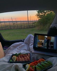 two trays of food sitting in the back of a car on top of a blanket