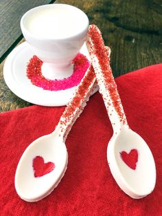 two spoons decorated with red glitter sit on a table next to a cup and saucer