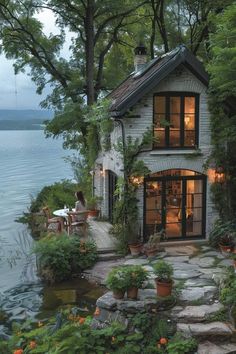 a small house sitting on top of a lush green hillside next to the water's edge