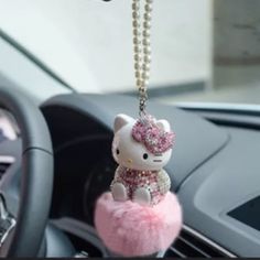 a hello kitty keychain hanging from the dashboard of a car with pearls on it