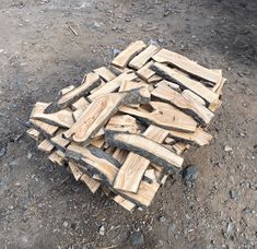 a pile of wood sitting on top of a dirt field