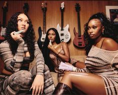 three beautiful women sitting next to each other in front of guitars