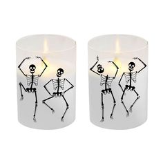 two candles with skeletons on them sitting next to each other in front of a white background