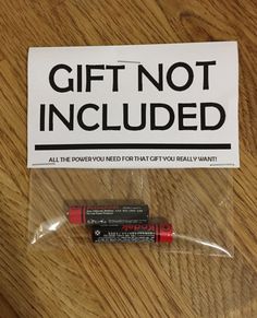 a gift not included sticker on a wooden table next to a red lip bale