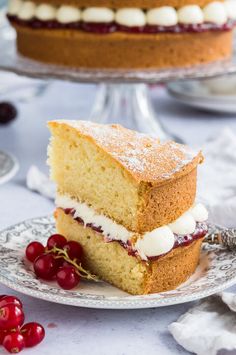 a piece of cake on a plate with cherries around it and another slice in the background