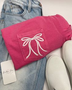 a pair of jeans and a pink pillow with a bow on it are sitting next to each other