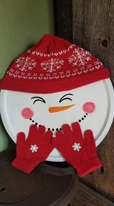 a white plate with a snowman face and red mittens on top of it