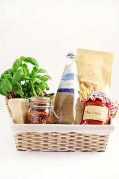 a wicker basket filled with different types of food and spices next to a potted plant