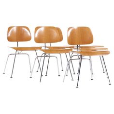 four eames chairs with metal legs and wooden seat covers, all in different colors