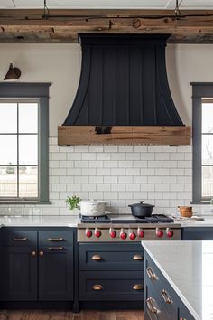 a kitchen with blue cabinets and an oven hood over the stove in front of two windows