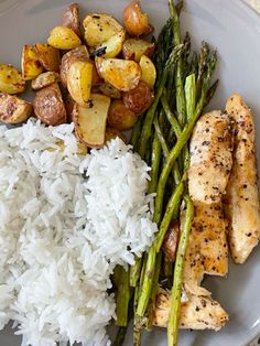 a white plate topped with chicken, rice and asparagus