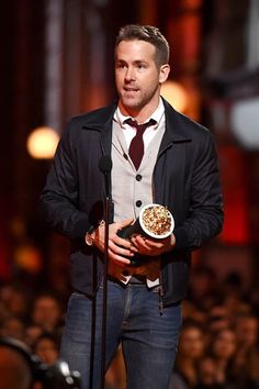 a man holding a bowl of popcorn while standing next to a microphone